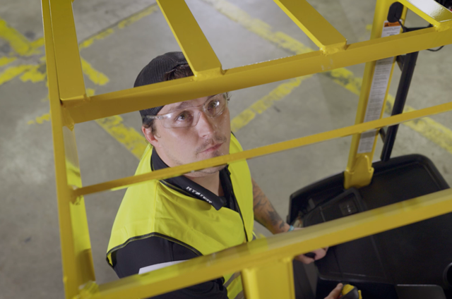 A forklift operator looks through overhead guard